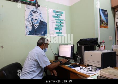 Palästinenser in der Nähe eines Wandbildes, das den verstorbenen palästinensischen Führer Yasser Arafat am 11. November 2021 in Rafah im südlichen Gazastreifen zeigt. Stockfoto