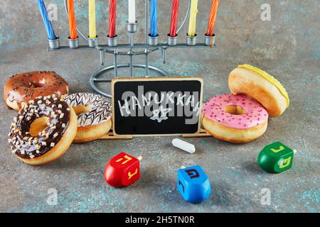 Happy Hanukkah und Hanukkah Sameach - traditioneller jüdischer Kerzenständer mit Kerzen, Donuts und Spinning Tops mit der Aufschrift Hanukkah. Stockfoto