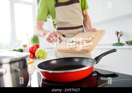 Cropped Foto Koch Mann Zugabe von geschnittenen Pilzen auf Bratpfanne Stockfoto