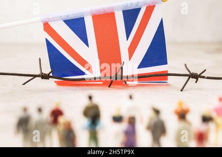 Britische Flagge, Stacheldraht und Plastikspielzeug Männer, illegale Migration Konzept Stockfoto