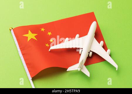 Flagge Chinas und ein Spielzeugflugzeug auf grünem Hintergrund, das Konzept zum Thema Reisen nach China und Inlandsflüge im Land Stockfoto