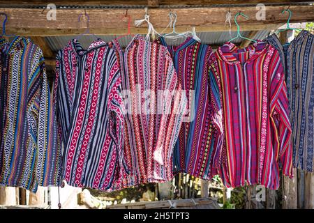 Bunte Bergsteiger-Hemden in Blau und Rot hängen auf einem Holzgestell des ländlichen Bekleidungsladens. Stockfoto