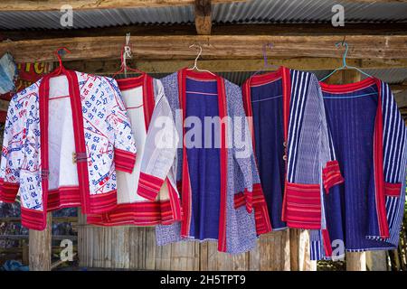 Bunte Bergsteiger-Hemden in Blau und Rot hängen auf einem Holzgestell des ländlichen Bekleidungsladens. Stockfoto