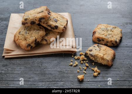 Kekse mit dunklen Schokoladenstückchen auf rustikalem Hintergrund Stockfoto