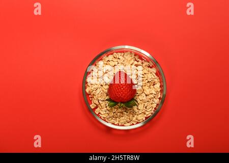 Erdbeeren und Haferflocken auf rotem Hintergrund Stockfoto