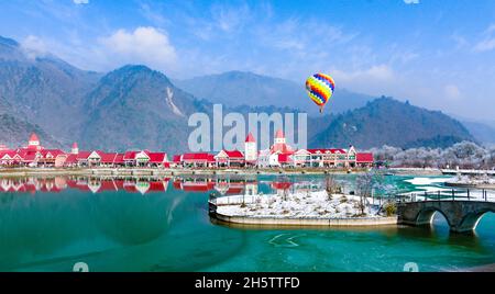 Der farbenfrohe Heißluftballon erhebt sich über der märchenhaften Landschaft des Xiling Snow Mountain und dem Resort in Chengdu, Sichuan, China Stockfoto