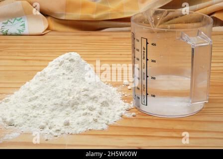 Behälter mit Wasser und Mehl für Blätterteig Rezept auf einem Holztisch Stockfoto