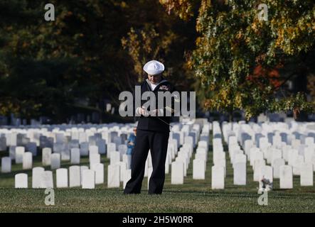 Arlington, USA. November 2021. Am 11. November 2021 hält sich ein US-Seemann inmitten von Gräbern auf dem Nationalfriedhof von Arlington in Arlington, VA, USA, an einer amerikanischen Flagge fest. Foto von Jonathan Ernst/Pool/ABACAPRESS.COM Quelle: Abaca Press/Alamy Live News Stockfoto