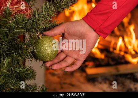 Nahaufnahme von Hand Platzierung einer Glühbirne mit Frost auf dem Zweig eines künstlichen Weihnachtsbaums, Details der schönen Dekoration für die Feier Stockfoto