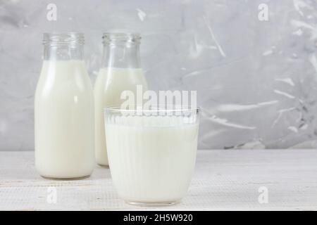 Köstliche frische Milch auf grauem Holzhintergrund. Ein Glas frischer Milch. Zwei Flaschen Bauernmilch. Platz zum Kopieren Stockfoto