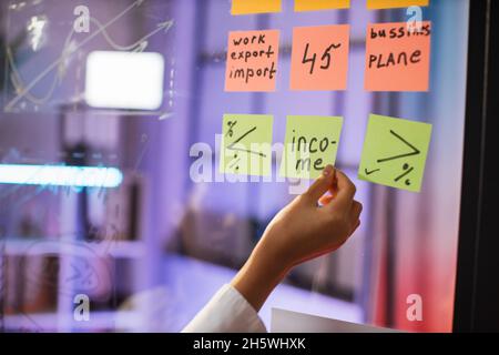 Nahaufnahme von weiblichen Handaufklebern auf transparentem Brett. Flipchart mit Finanzstrategie für die Unternehmensentwicklung. Business Meeting-Konzept. Stockfoto