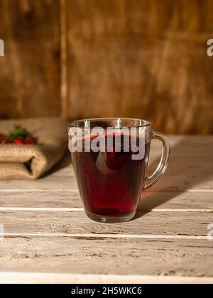 Natürlicher Tee aus wilden Rosenbeeren auf Holzbrettern. Homöopathie Behandlung von roten Beeren. Stockfoto