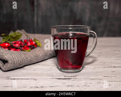 Natürlicher Tee aus wilden Rosenbeeren auf Holzbrettern. Homöopathie Behandlung von roten Beeren. Stockfoto