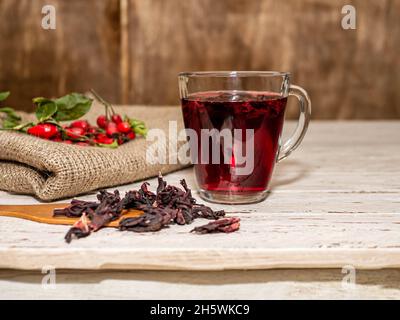 Natürlicher Tee aus wilden Rosenbeeren auf Holzbrettern. Homöopathie Behandlung von roten Beeren. Stockfoto