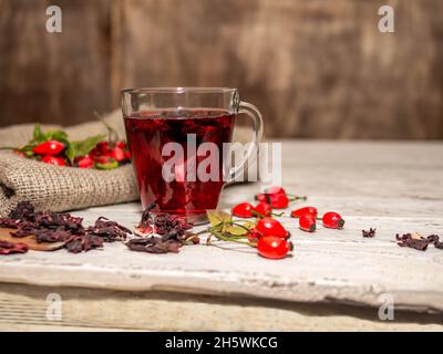 Natürlicher Tee aus wilden Rosenbeeren auf Holzbrettern. Homöopathie Behandlung von roten Beeren. Stockfoto