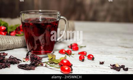 Natürlicher Tee aus wilden Rosenbeeren auf Holzbrettern. Homöopathie Behandlung von roten Beeren. Stockfoto