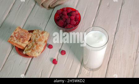 Frische Milch im Glas auf alten Holzbrettern. Milch mit Malz auf einem Teller, Fruchtjoghurt Stockfoto