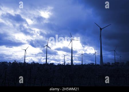 Windmühlen, die Strom produzieren, werden in einem dunkelblauen Himmel dargestellt Stockfoto