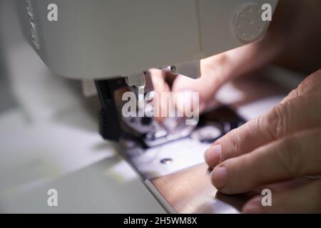 Der Arbeitsplatz einer Näherin. Der Schneidermeister arbeitet an einer Nähmaschine. Ein Schneider näht Kleidung an seinem Arbeitsplatz. Hobby-Nähen als Kleinbetrieb-Konzept. Hochwertige Fotos Stockfoto