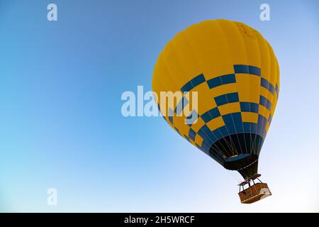 Heißluftballon. Gelbe Heißluftballon mit blauen Streifen Hintergrund Foto. Hintergrundbild für Reisen, Tourismus oder Flugaktivitäten. Adventure Konz Stockfoto