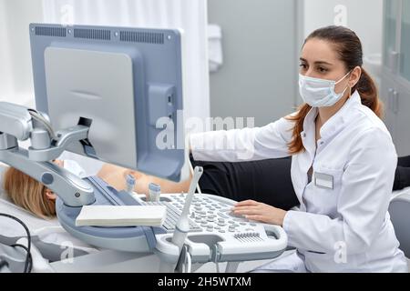 Die Ärztin gibt dem Patienten einen weiblichen Abdominalsonographie. Ultraschallscanner in den Händen eines Arztes Stockfoto