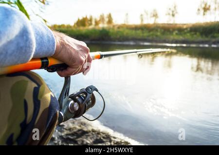 Hände des Fischers halten Angelrute mit Haspel Stockfoto