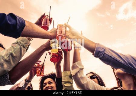 Fröhliche Menschen, die im Freien Cocktails in Plastikgläsern toasten - Treffen von multikulturellen Freunden, die Spaß beim Trinken von alkoholischen Getränken haben Stockfoto