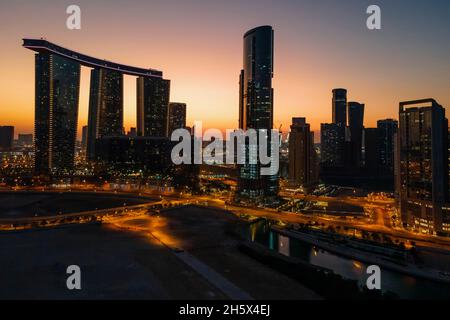 Zauberhafter Sonnenuntergang auf der Insel Al Reem in Abu Dhabi. Luftaufnahme der silhouettierten modernen Wolkenkratzer. Stockfoto
