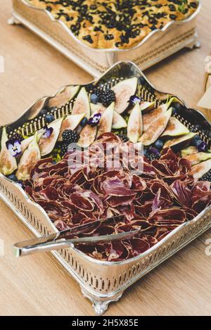 Vertikale Aufnahme von Pastrami-Scheiben mit Passionsfrucht und Brombeeren auf einem Tablett Stockfoto