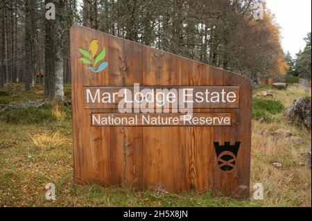 Schild für Mar Lodge Estate National Nature Reserve mit verschwommenem Hintergrund aus Gras, Wald und Straße. Stockfoto