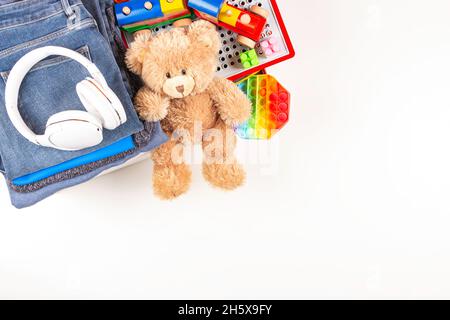 Spende, Wohltätigkeitskonzept. Spendenboxen mit Kleidung und Kinderspielzeug auf weißem Tisch. Draufsicht, Kopierbereich Stockfoto