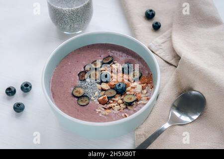 Gesunde, geglättet Schüssel mit Chiasamen, Heidelbeeren, Nüssen und Erdnussbutter. Veganes Frühstück, Blick von oben Stockfoto