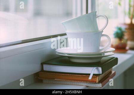 Zwei Teetassen aus Porzellan mit Untertassen auf der Fensterbank Stockfoto