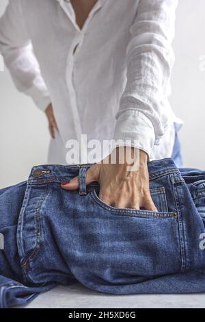 Crop unkenntlich weiblich in weißem Hemd setzen Hand in die Tasche der blauen Jeans Stockfoto