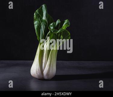 Gesundes frisches Kohl-Kohlblatt-Gemüse auf schwarzem Tisch vor dunklem Hintergrund platziert Stockfoto