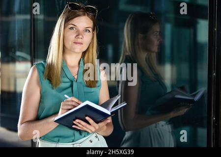 Notizblock in den Händen einer jungen Frau im Business-Anzug. Stockfoto