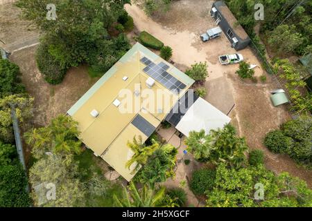 Draufsicht auf das Dach eines Hauses mit Solarzellen und einem großen Hof mit Schuppen und Fahrzeugen Stockfoto