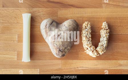 Eine „Ich liebe dich“-Nachricht, die mit Lebensmitteln wie einem Mozzarella-Stringkäsestab, herzförmigen Kartoffeln und Müsliriegel in Form eines U geschrieben wird Stockfoto