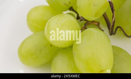 Frische Trauben rotieren auf weißem Hintergrund. Reife saftige Trauben rotieren auf einem Teller. Nahaufnahme eines Bukets weißer Trauben. Stockfoto