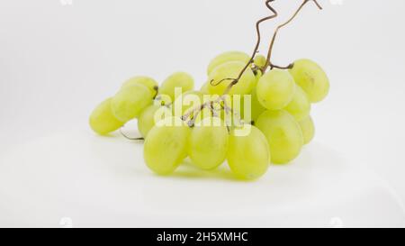 Frische Trauben rotieren auf weißem Hintergrund. Reife saftige Trauben rotieren auf einem Teller. Nahaufnahme eines Bukets weißer Trauben. Stockfoto