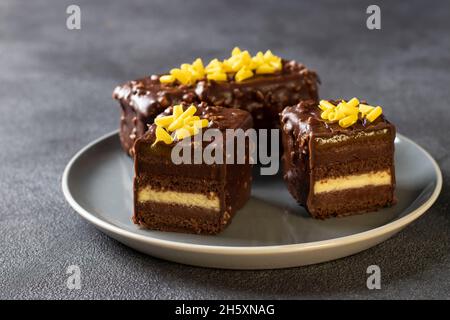 Schokoladenmandel-Brownie mit Mango- und Passionsfrucht-Konfitüre überzogen Gourmet-Schokoladenglasur auf grauem Hintergrund Stockfoto