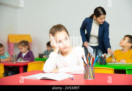 Verärgert Schulmädchen sitzt an einem Schreibtisch in Klassenzimmer Grundschule Stockfoto