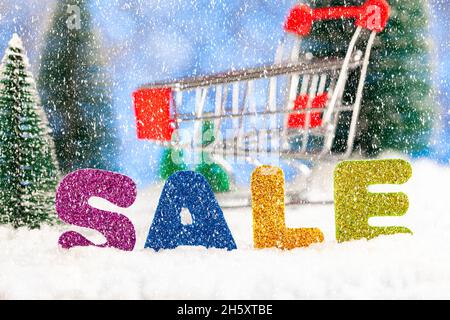 Weihnachtsangebot. Supermarkt Trolley und Inschrift VERKAUF im Schnee, es schneit Stockfoto