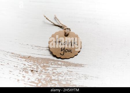 Dankeswort in einer Karte auf weißem Holzhintergrund geschrieben. Stockfoto