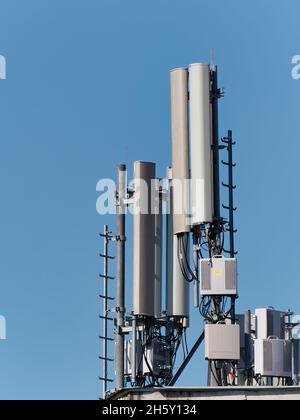 Vertikale Aufnahme einer Mobilfunk-Basisstation vor blauem Himmel Stockfoto