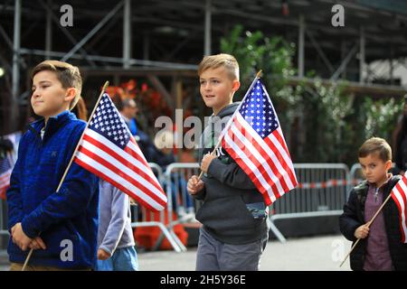 New York, N.Y/USA – 11. November 2021: Ein Kind schwingt während der Veterans Day Parade auf der Fifth Avenue in New York am 11. November 2021 die Flagge der Vereinigten Staaten. Quelle: Gordon Donovan/Alamy Live News) Stockfoto