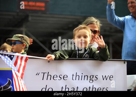 New York, N.Y/USA – 11. November 2021: Ein Kind schwingt während der Veterans Day Parade auf der Fifth Avenue in New York am 11. November 2021 die Flagge der Vereinigten Staaten. Quelle: Gordon Donovan/Alamy Live News) Stockfoto