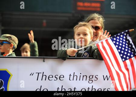New York, N.Y/USA – 11. November 2021: Ein Kind schwingt während der Veterans Day Parade auf der Fifth Avenue in New York am 11. November 2021 die Flagge der Vereinigten Staaten. Quelle: Gordon Donovan/Alamy Live News) Stockfoto