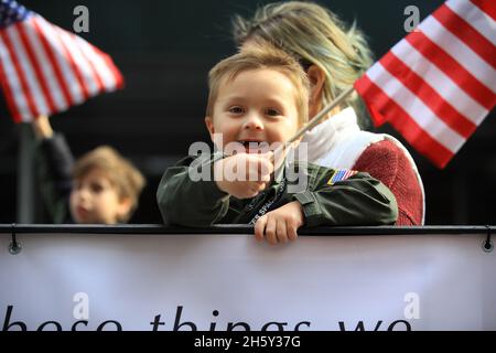 New York, N.Y/USA – 11. November 2021: Ein Kind schwingt während der Veterans Day Parade auf der Fifth Avenue in New York am 11. November 2021 die Flagge der Vereinigten Staaten. Quelle: Gordon Donovan/Alamy Live News) Stockfoto