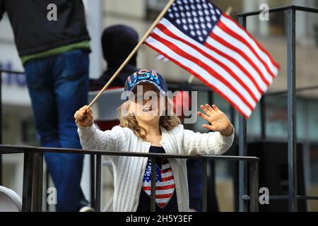 New York, N.Y/USA – 11. November 2021: Ein Kind schwingt während der Veterans Day Parade auf der Fifth Avenue in New York am 11. November 2021 die Flagge der Vereinigten Staaten. Quelle: Gordon Donovan/Alamy Live News) Stockfoto